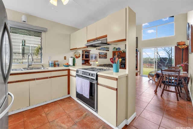 94-517 Poloahilani St, Mililani, HI 96789 - kitchen with gas range, freestanding refrigerator, light countertops, a ceiling fan, and under cabinet range hood