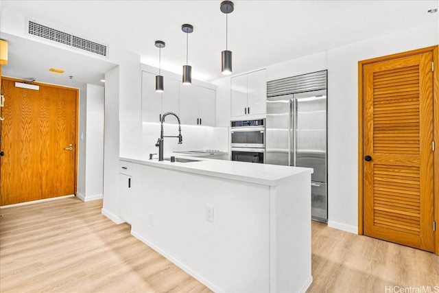 1330 Ala Moana Blvd Unit 1907, Honolulu, HI 96814 - kitchen with stainless steel appliances, light countertops, white cabinets, a peninsula, and light wood finished floors