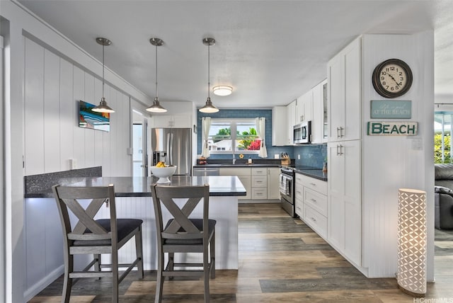 46-146 Hinalani Pl, Kaneohe, HI 96744 - kitchen featuring stainless steel appliances, a peninsula, dark countertops, a breakfast bar area, and white cabinetry