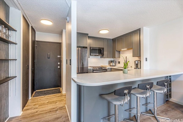 400 Hobron Ln Unit 603, Honolulu, HI 96815 - kitchen with stainless steel appliances, light wood-style flooring, a breakfast bar, light countertops, and a textured ceiling