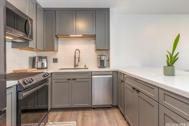 400 Hobron Ln Unit 603, Honolulu, HI 96815 - kitchen featuring stainless steel appliances, gray cabinets, light wood finished floors, and backsplash