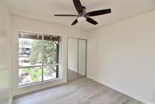 91-1180 Puamaeole St Unit 10T, Ewa Beach, HI 96706 - unfurnished bedroom with a textured ceiling, wood finished floors, a ceiling fan, and a closet
