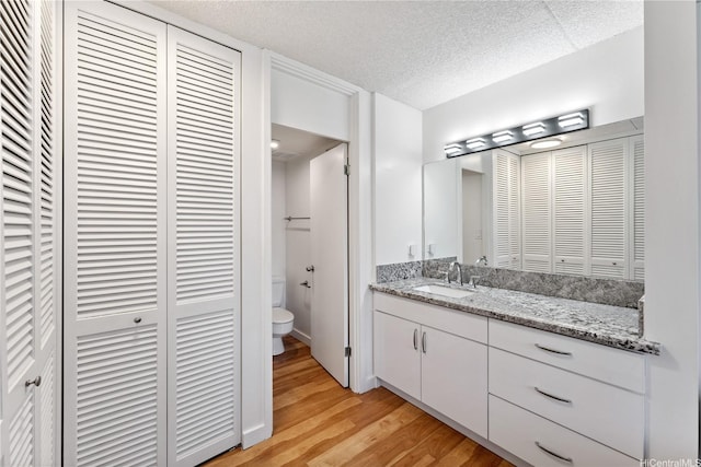 469 Ena Rd Unit 1111, Honolulu, HI 96815 - bathroom featuring a closet, vanity, wood finished floors, and a textured ceiling