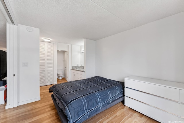 469 Ena Rd Unit 1111, Honolulu, HI 96815 - bedroom with light wood-type flooring, a textured ceiling, and ensuite bathroom