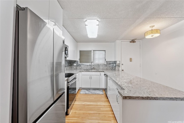 469 Ena Rd Unit 1111, Honolulu, HI 96815 - kitchen with stainless steel appliances, a peninsula, a textured ceiling, white cabinets, and light wood-style flooring