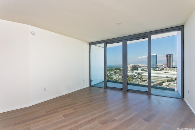1000 Auahi St Unit 1805, Honolulu, HI 96814 - spare room featuring a wall of windows, wood finished floors, a view of city, and a smoke detector
