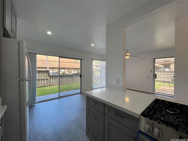 91-1089 Puamaeole St Unit 15D, Ewa Beach, HI 96706 - kitchen with freestanding refrigerator, stainless steel gas range, light stone countertops, wood finished floors, and a ceiling fan