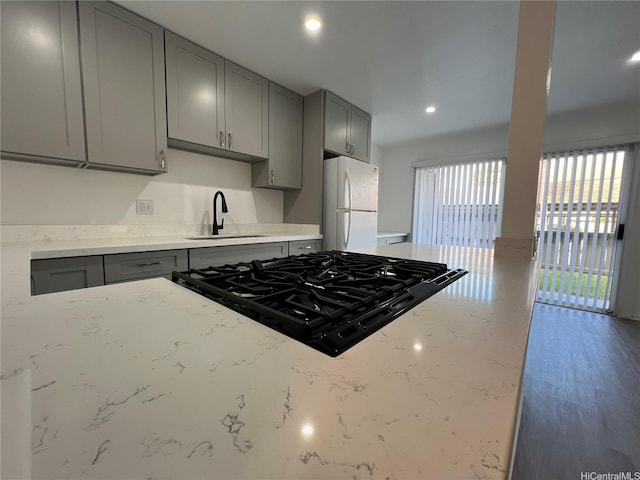 91-1089 Puamaeole St Unit 15D, Ewa Beach, HI 96706 - kitchen with gray cabinetry, freestanding refrigerator, light stone countertops, black gas stovetop, and recessed lighting