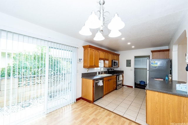94-725 Kumau Pl, Waipahu, HI 96797 - kitchen with stainless steel appliances, dark countertops, a chandelier, and brown cabinetry