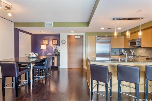 1837 Kalakaua Ave Unit 808, Honolulu, HI 96815 - kitchen with appliances with stainless steel finishes, dark wood-style floors, stone countertops, a kitchen bar, and decorative backsplash