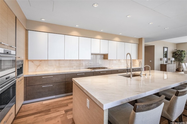 1555 Kapiolani Blvd Unit 2302, Honolulu, HI 96814 - kitchen featuring modern cabinets, light wood-style floors, a breakfast bar, tasteful backsplash, and recessed lighting