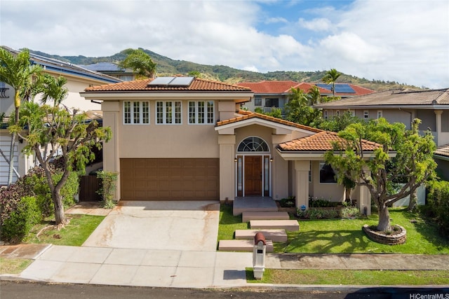 92-1318 Hauone St, Kapolei, HI 96707 - mediterranean / spanish-style house with a tile roof, roof mounted solar panels, a garage, concrete driveway, and a front lawn