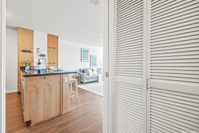 1133 Waimanu St Unit 2503, Honolulu, HI 96814 - kitchen featuring wood finished floors, a kitchen breakfast bar, open floor plan, and a textured ceiling
