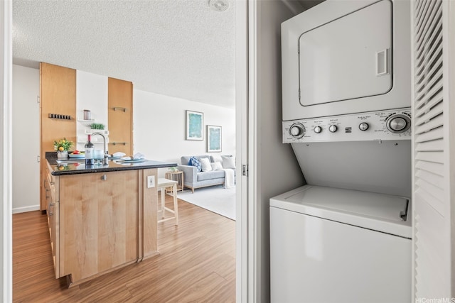 1133 Waimanu St Unit 2503, Honolulu, HI 96814 - laundry room with stacked washing machine and dryer, light wood-type flooring, and a textured ceiling