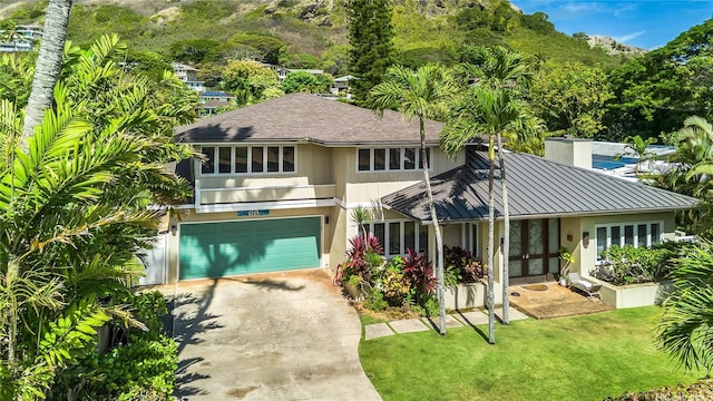 1319 Mokulua Dr, Kailua, HI 96734 - view of front of house with concrete driveway, a garage, a front lawn, a standing seam roof, and french doors