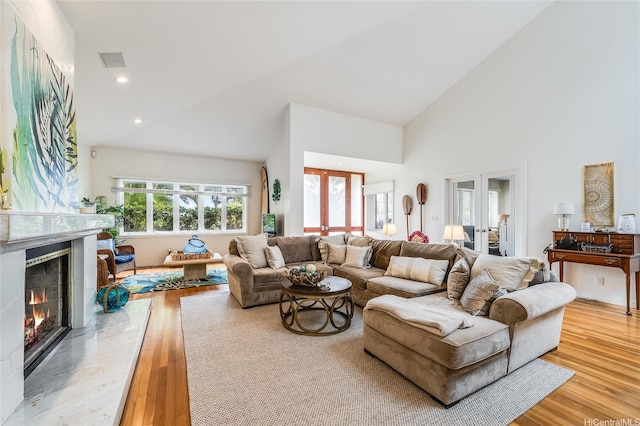 1319 Mokulua Dr, Kailua, HI 96734 - living area with light wood-type flooring, french doors, a high end fireplace, high vaulted ceiling, and recessed lighting