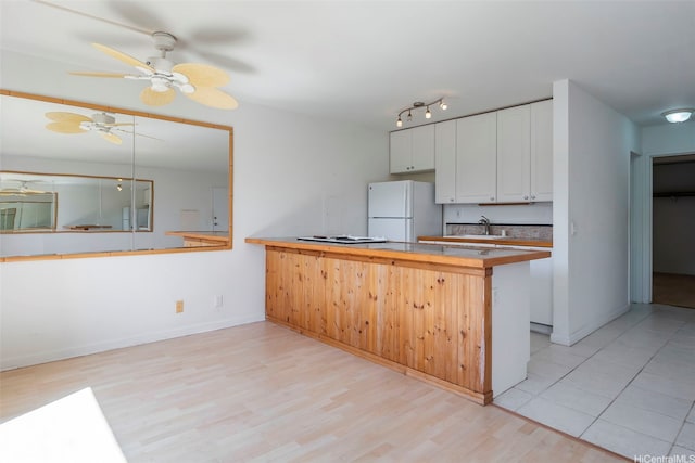 84-755 Ala Mahiku St Unit 74B, Waianae, HI 96792 - kitchen featuring freestanding refrigerator, a peninsula, a ceiling fan, white cabinetry, and light wood-style floors
