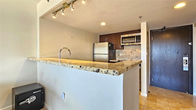 1777 Ala Moana Blvd Unit 2436, Honolulu, HI 96815 - kitchen with stainless steel microwave, freestanding refrigerator, backsplash, dark brown cabinetry, and track lighting