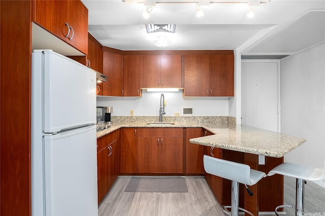 225 Queen St Unit 9E, Honolulu, HI 96813 - kitchen with freestanding refrigerator, a peninsula, light wood finished floors, light stone counters, and brown cabinetry