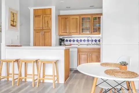 57-101 Kuilima Dr Unit 168, Kahuku, HI 96731 - bar area featuring light wood-type flooring, dishwasher, and backsplash