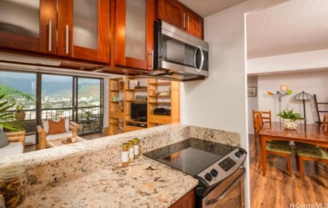 2333 Kapiolani Blvd Unit 2707, Honolulu, HI 96826 - kitchen with stainless steel appliances, brown cabinetry, light stone counters, and wood finished floors