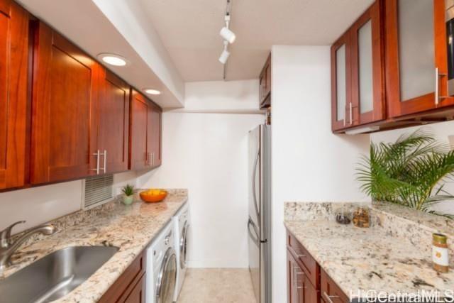 2333 Kapiolani Blvd Unit 2707, Honolulu, HI 96826 - kitchen with freestanding refrigerator, track lighting, light stone countertops, washing machine and dryer, and glass insert cabinets