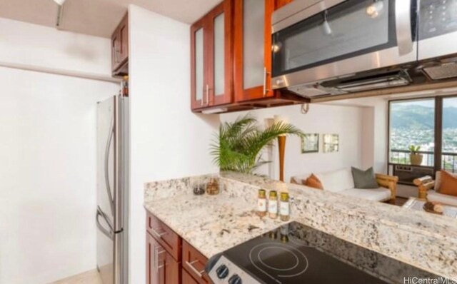 2333 Kapiolani Blvd Unit 2707, Honolulu, HI 96826 - kitchen with appliances with stainless steel finishes, brown cabinetry, glass insert cabinets, and light stone counters