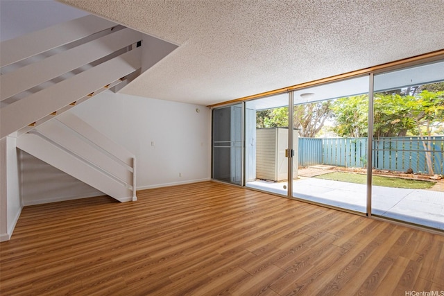 95-312 Kahikinui Ct Unit 213, Mililani, HI 96789 - unfurnished living room featuring wood finished floors, expansive windows, a textured ceiling, and stairs