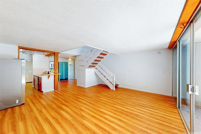 95-312 Kahikinui Ct Unit 213, Mililani, HI 96789 - unfurnished living room with a textured ceiling, light wood-style flooring, ceiling fan, and stairway