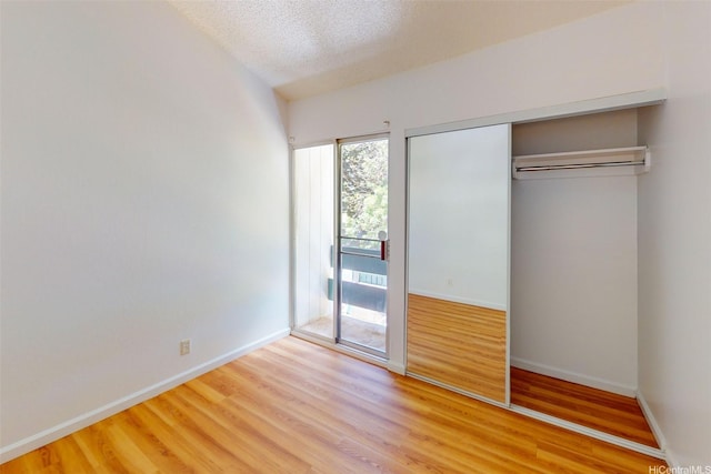 95-312 Kahikinui Ct Unit 213, Mililani, HI 96789 - unfurnished bedroom featuring wood finished floors, access to exterior, a closet, and a textured ceiling