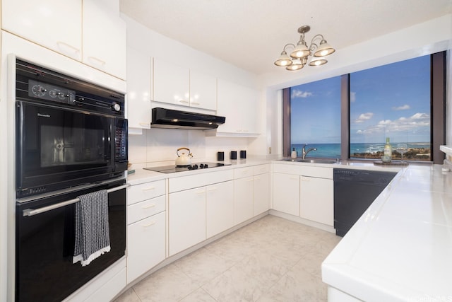 425 S St Unit 2401, Honolulu, HI 96813 - kitchen with black appliances, under cabinet range hood, white cabinetry, light countertops, and a chandelier