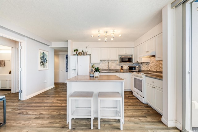 801 S St Unit 3822, Honolulu, HI 96813 - kitchen featuring white appliances, under cabinet range hood, backsplash, a center island, and white cabinets