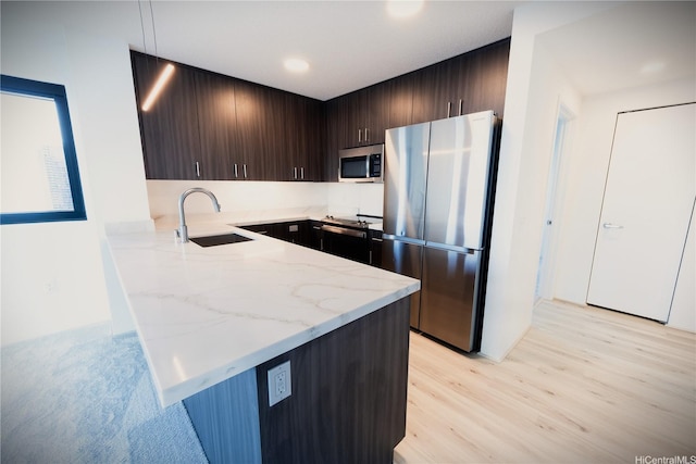 615 Keawe St Unit 3207, Honolulu, HI 96813 - kitchen featuring stainless steel appliances, a peninsula, dark brown cabinetry, light stone counters, and light wood finished floors