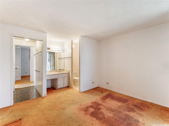 1160 Ala Napunani St Unit 1407, Honolulu, HI 96818 - unfurnished bedroom featuring light carpet, ensuite bathroom, a textured ceiling, and a desk