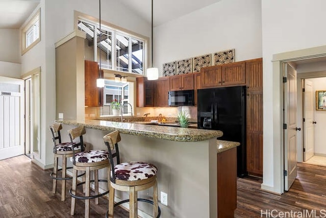 75-6025 Alii Dr Unit L201, Kailua Kona, HI 96740 - kitchen featuring a high ceiling, black appliances, dark wood-style floors, brown cabinets, and light stone countertops