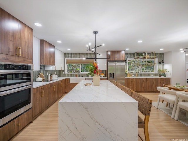 3641 Kumuone St, Honolulu, HI 96822 - kitchen with stainless steel appliances, decorative backsplash, brown cabinets, light wood-style flooring, and a center island
