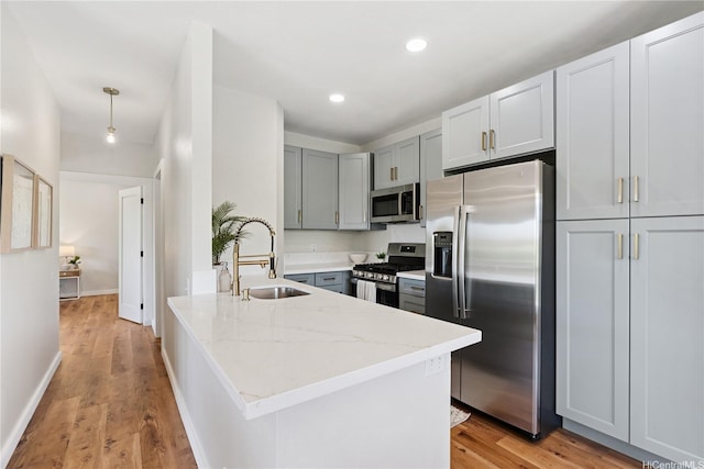 91-985 Puahala St Unit 42R, Ewa Beach, HI 96706 - kitchen with stainless steel appliances, a peninsula, light stone counters, gray cabinetry, and light wood-type flooring