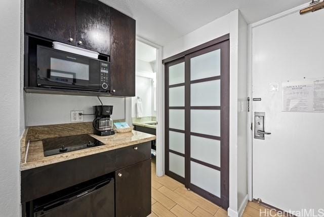 445 Seaside Ave Unit 2608, Honolulu, HI 96815 - kitchen with black appliances, light wood finished floors, and light stone counters