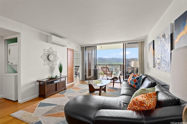 990 Ala Nanala St Unit 35B, Honolulu, HI 96818 - living room featuring stacked washer / dryer, a wall unit AC, wood finished floors, expansive windows, and a mountain view
