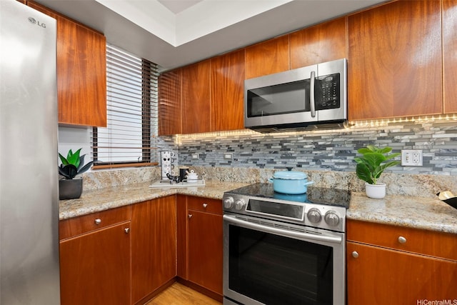 990 Ala Nanala St Unit 35B, Honolulu, HI 96818 - kitchen featuring stainless steel appliances, tasteful backsplash, brown cabinets, and light stone countertops