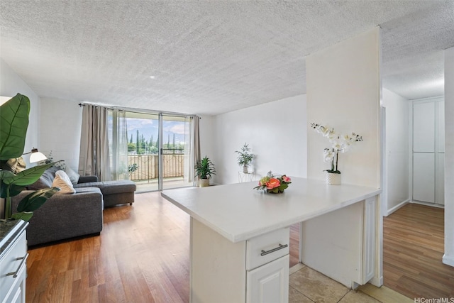 1830 Wilikina Dr Unit 602, Wahiawa, HI 96786 - kitchen with a peninsula, a textured ceiling, open floor plan, light wood-style floors, and light countertops