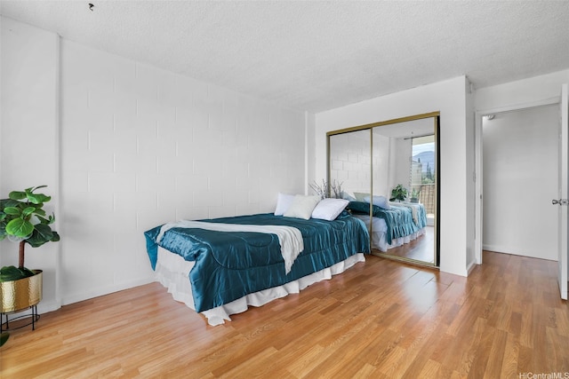 1830 Wilikina Dr Unit 602, Wahiawa, HI 96786 - bedroom featuring light wood-style flooring, a textured ceiling, concrete block wall, a closet, and access to outside