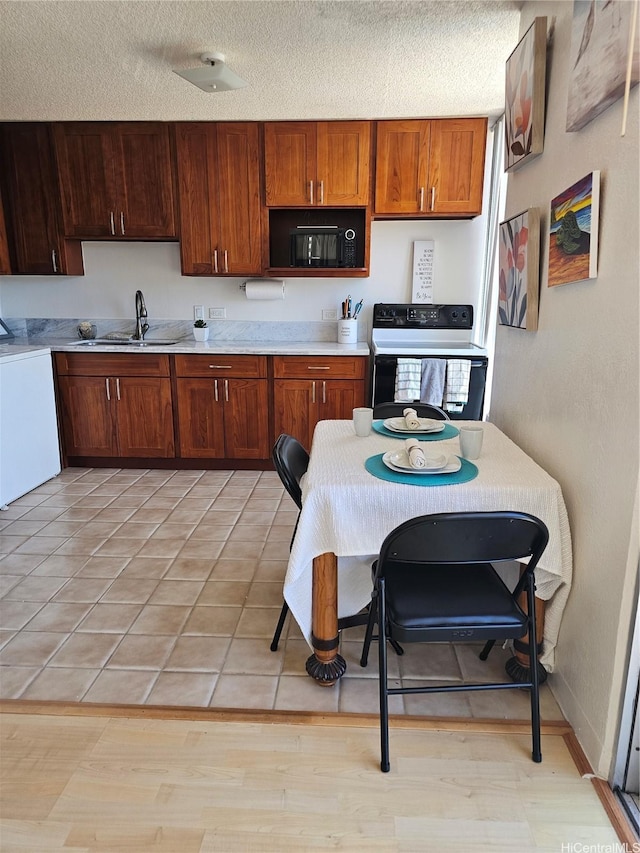 1702 Kewalo St Unit 204, Honolulu, HI 96822 - kitchen with range with electric cooktop, washer / clothes dryer, light countertops, a textured ceiling, and brown cabinets