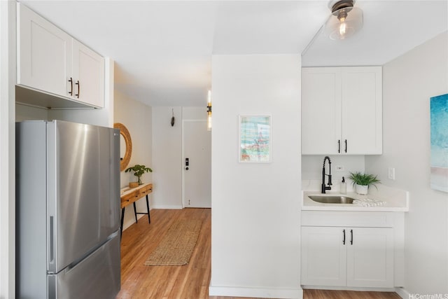 53-549 Kamehameha Hwy Unit 313, Hauula, HI 96717 - kitchen featuring freestanding refrigerator, light countertops, light wood-type flooring, and white cabinetry