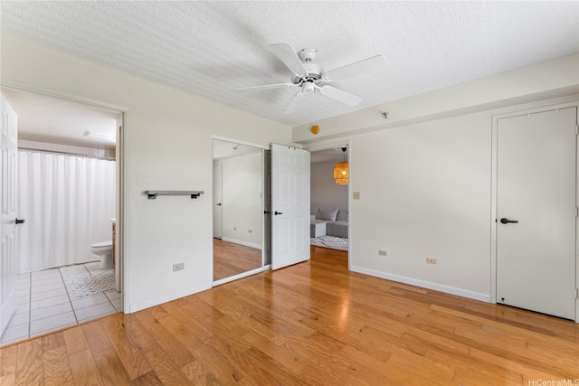 3075 Ala Poha Pl Unit 206, Honolulu, HI 96818 - unfurnished bedroom featuring light wood-type flooring, a textured ceiling, ensuite bathroom, and ceiling fan