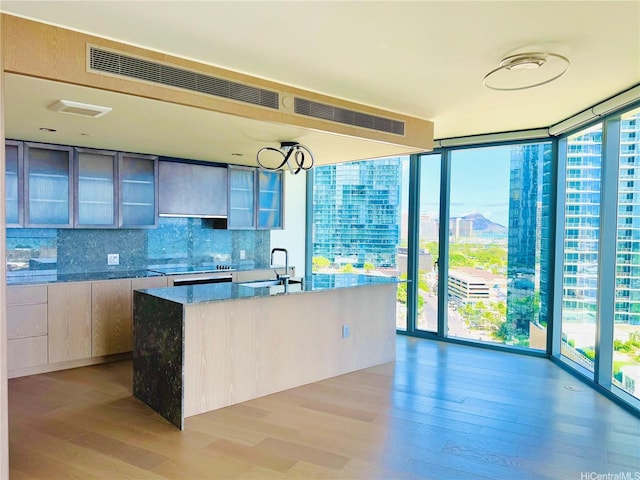 1000 Auahi St Unit 1600, Honolulu, HI 96814 - kitchen featuring floor to ceiling windows, healthy amount of natural light, light wood finished floors, tasteful backsplash, and glass insert cabinets