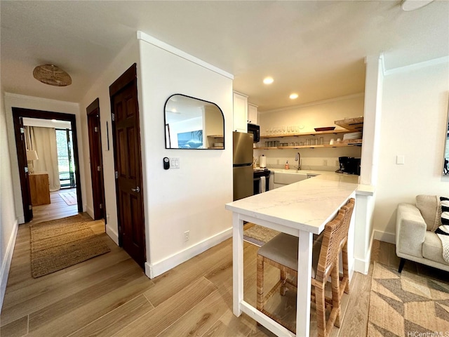 57-68 Eleku Kuilima Pl Unit 657, Kahuku, HI 96731 - kitchen with freestanding refrigerator, light wood-style floors, electric range, white cabinetry, and a peninsula