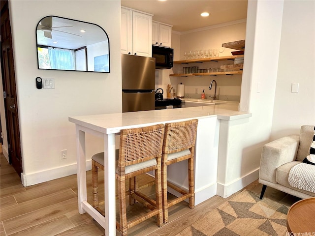 57-68 Eleku Kuilima Pl Unit 657, Kahuku, HI 96731 - kitchen featuring black microwave, freestanding refrigerator, light countertops, white cabinets, and ornamental molding