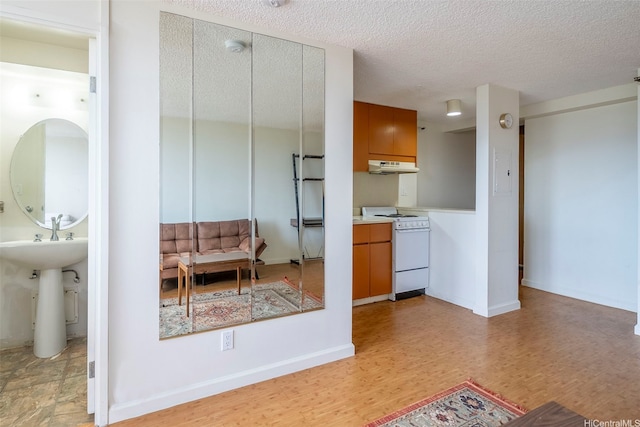 1060 Kamehameha Hwy Unit 2308B, Pearl City, HI 96782 - kitchen featuring white range oven, under cabinet range hood, brown cabinetry, a textured ceiling, and light wood-style flooring