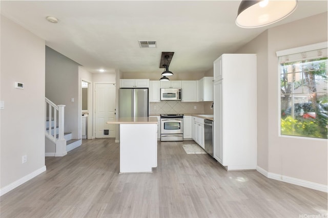 91-2070 Kaioli St Unit 4404, Ewa Beach, HI 96706 - kitchen with appliances with stainless steel finishes, white cabinetry, tasteful backsplash, a kitchen island, and light wood-style floors